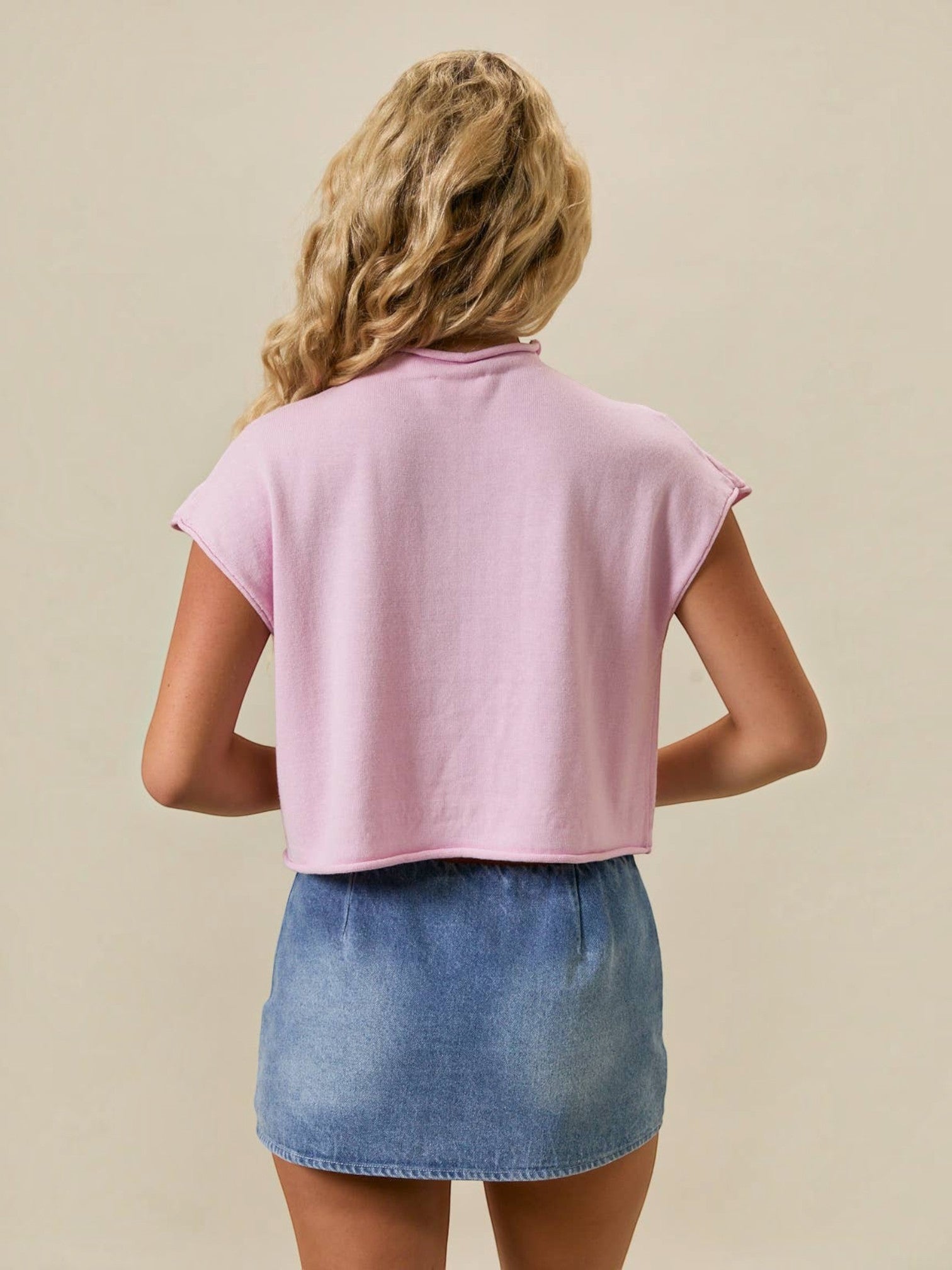 Back view of Mialur pink mock neck top with relaxed drop shoulder fit worn with a denim skirt