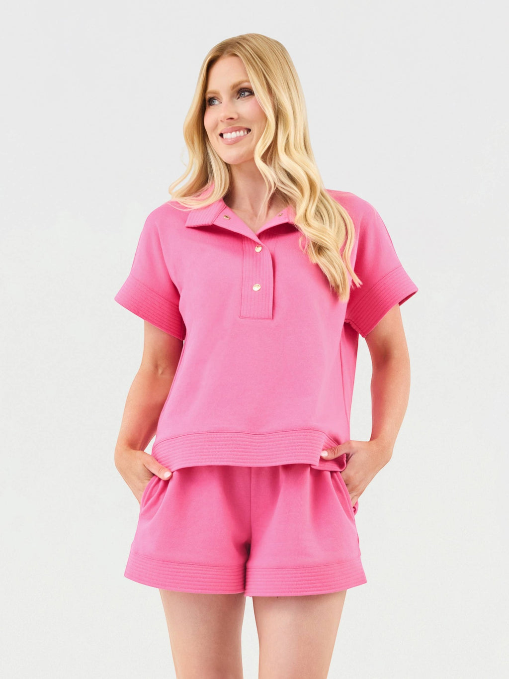 Model wearing Mialur pink two-piece set with collared short-sleeve top, gold buttons, and matching drawstring shorts.