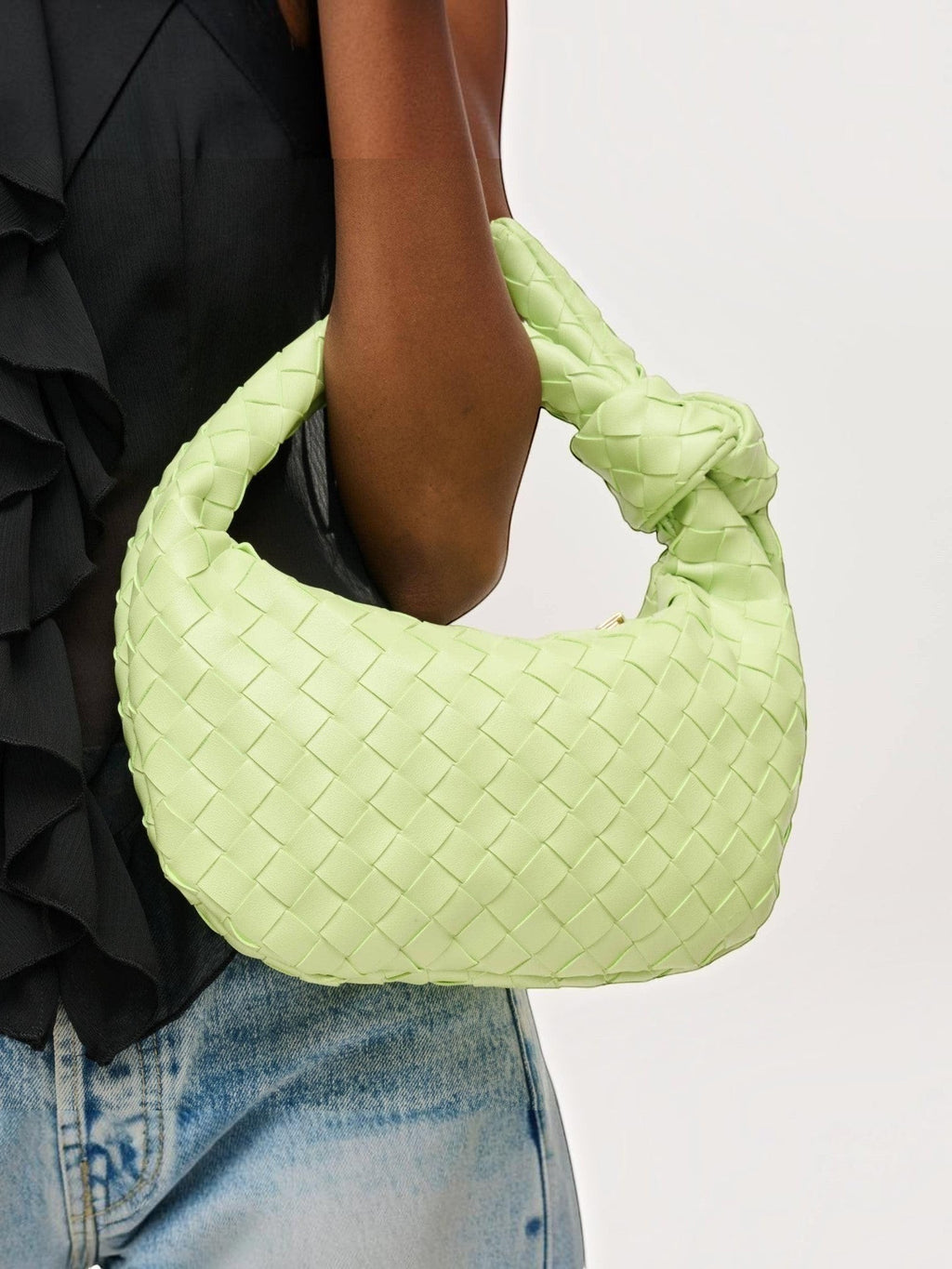 Mialur Pistachio Luxe Knot Clutch in woven vegan leather with a signature knotted handle, held by a model.