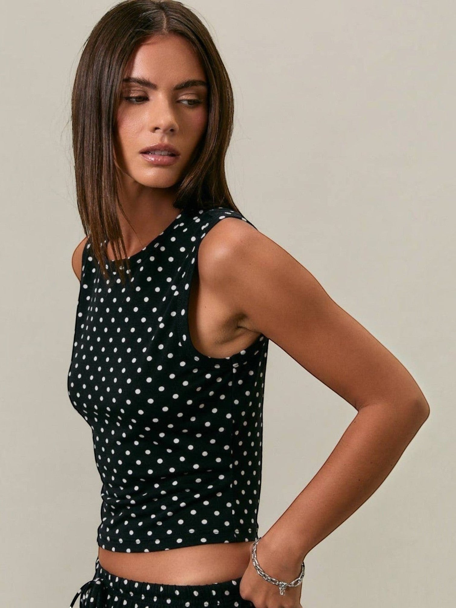 Mialur model wearing a fitted black and white polka dot stretch knit tank top with a round neckline.