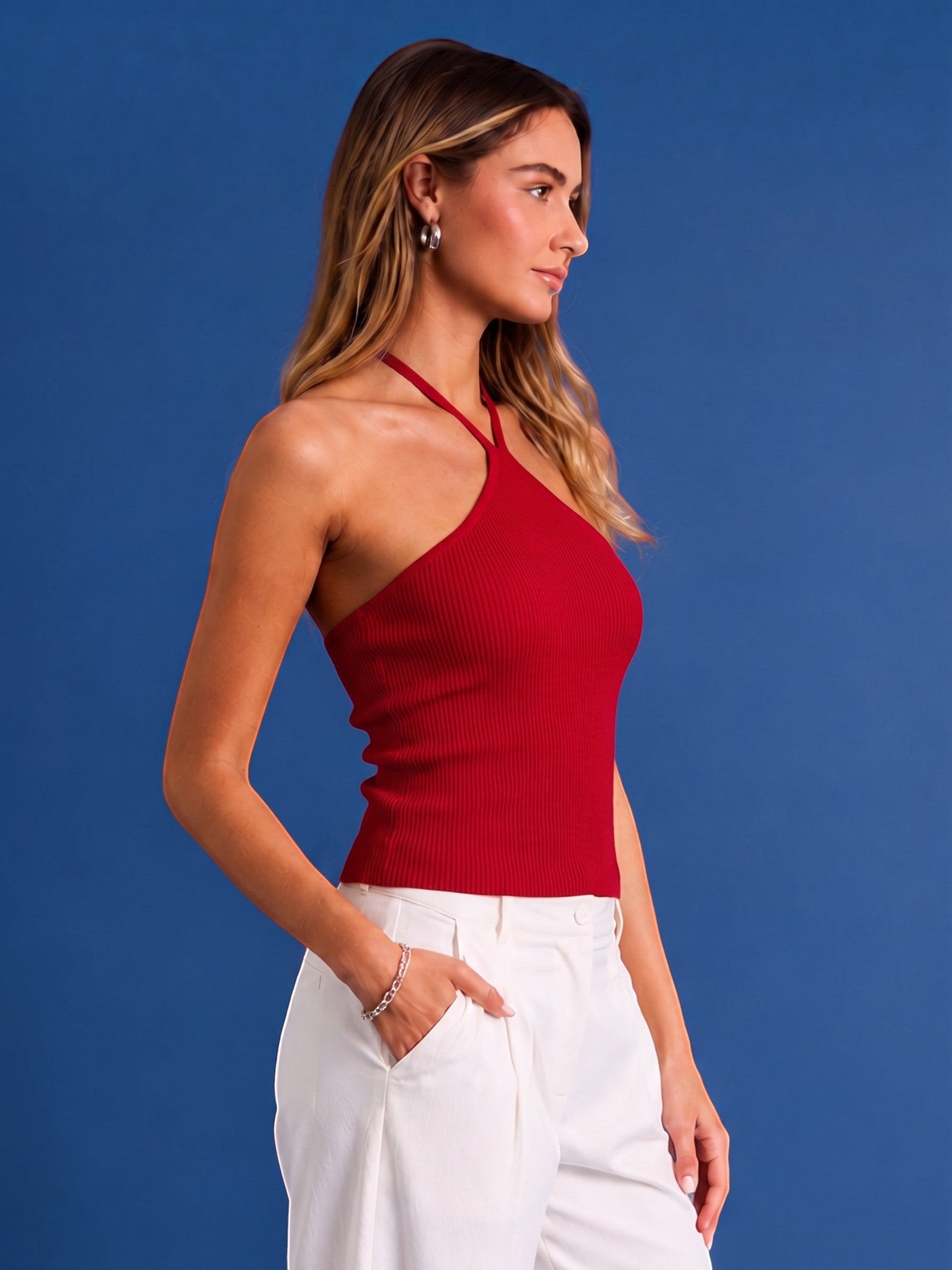 Model wearing a Mialur red ribbed halter top with a fitted silhouette, styled with white trousers against blue background