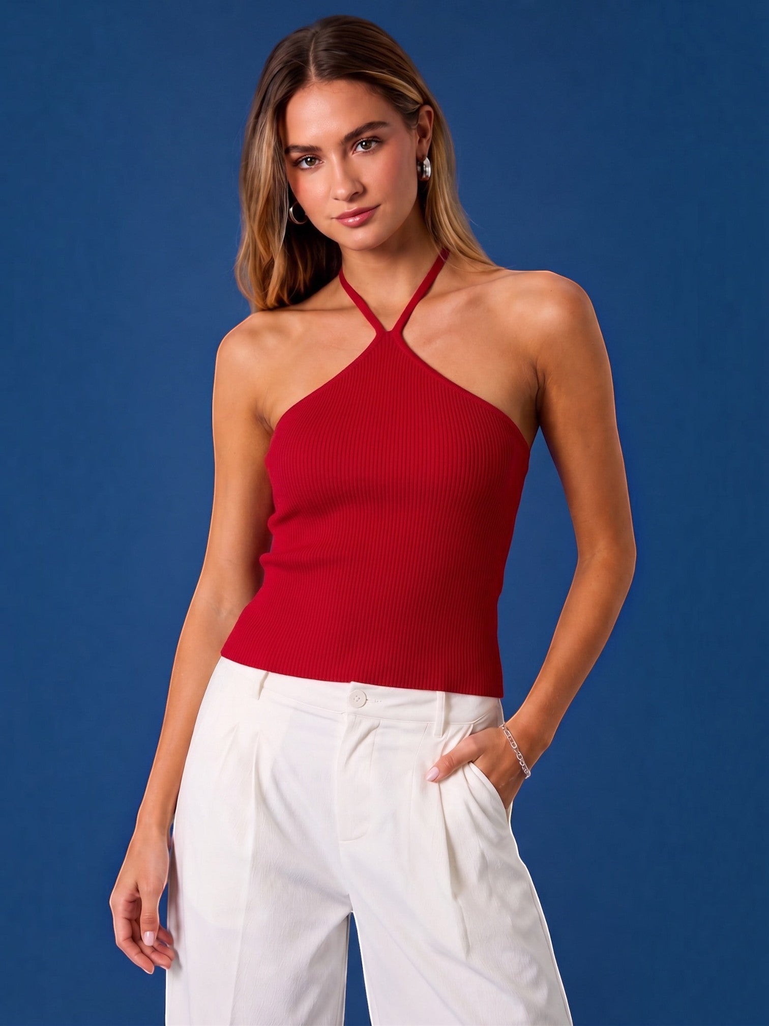 Mialur red ribbed halter top worn by a model with white trousers against a blue background