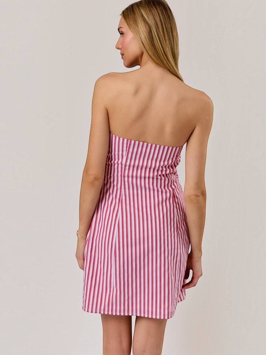 Model wearing Mialur strapless mini dress in red and white vertical stripes with a fitted ruched bodice back view