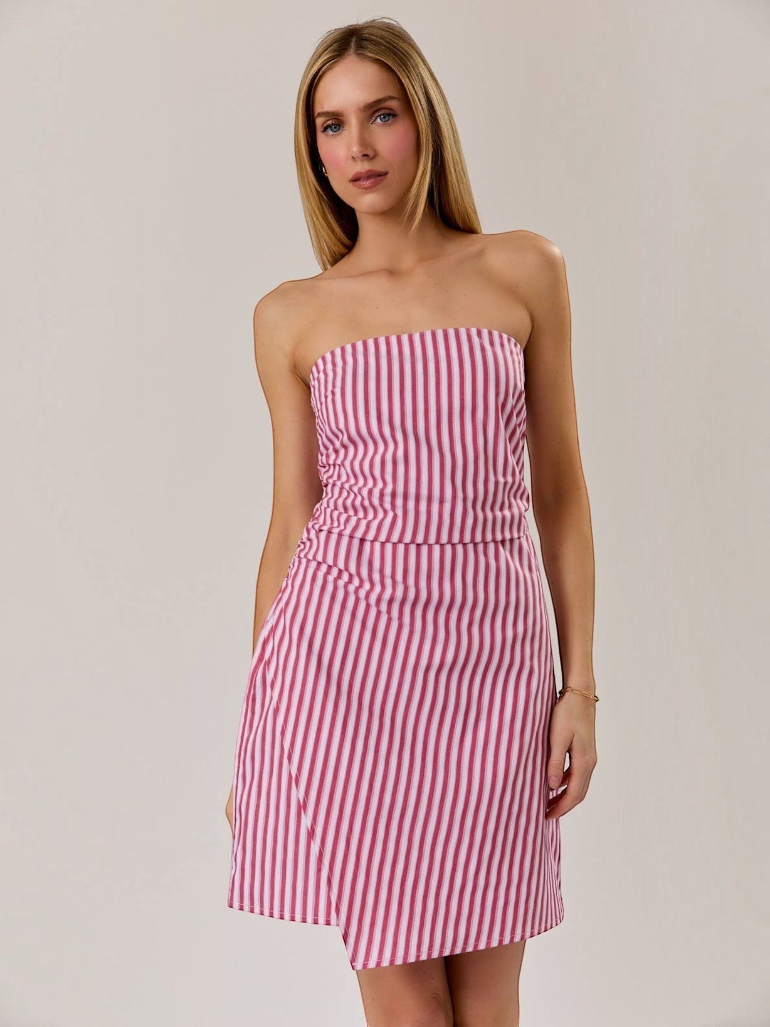 Model wearing a Mialur red and white vertical striped strapless mini dress with a flattering ruched bodice