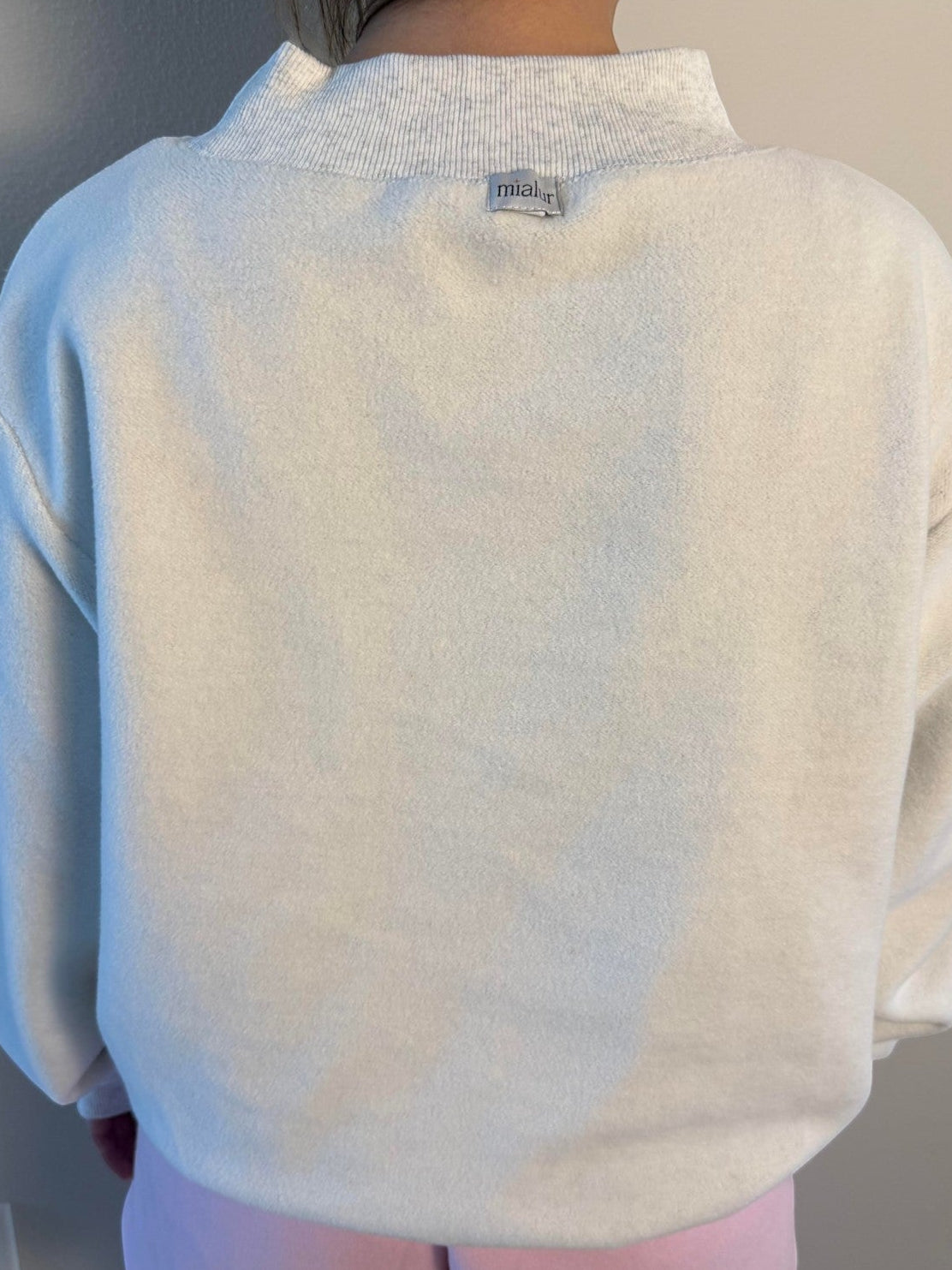 Mialur reversible mock neck top in cream worn by a person, showing the back view with a small branded label.