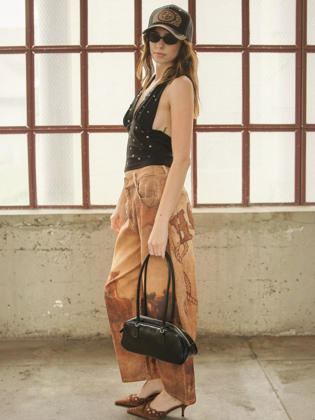 Mialur Roxie Halter black studded top with deep plunge neckline worn by a model with patterned pants and a handbag