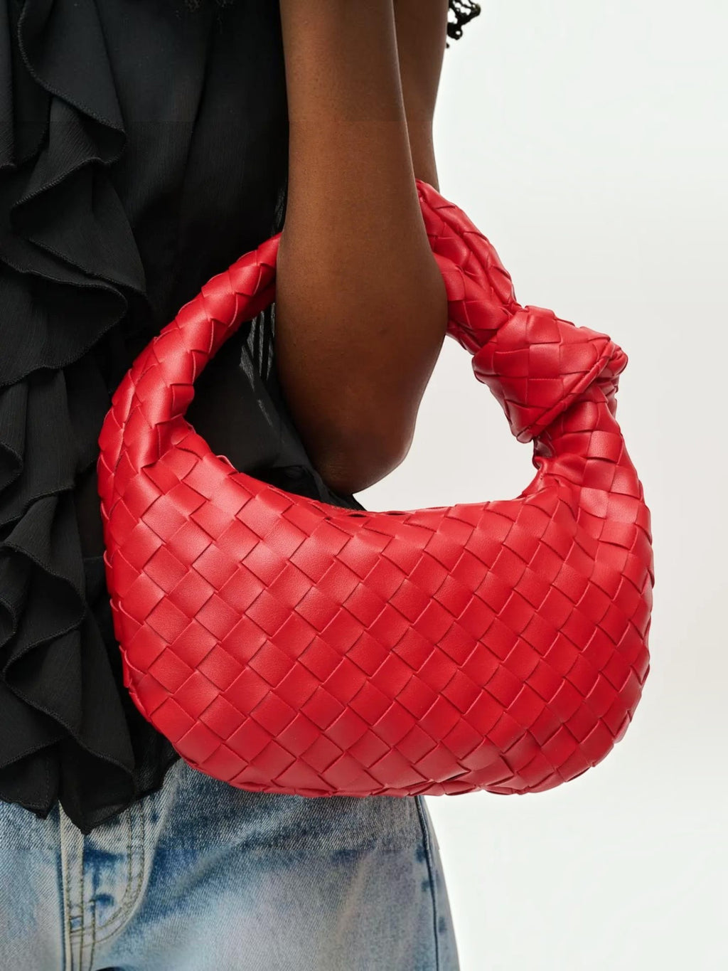Mialur Ruby Luxe Knot Clutch in ruby red woven vegan leather with a signature knot handle held by a model.