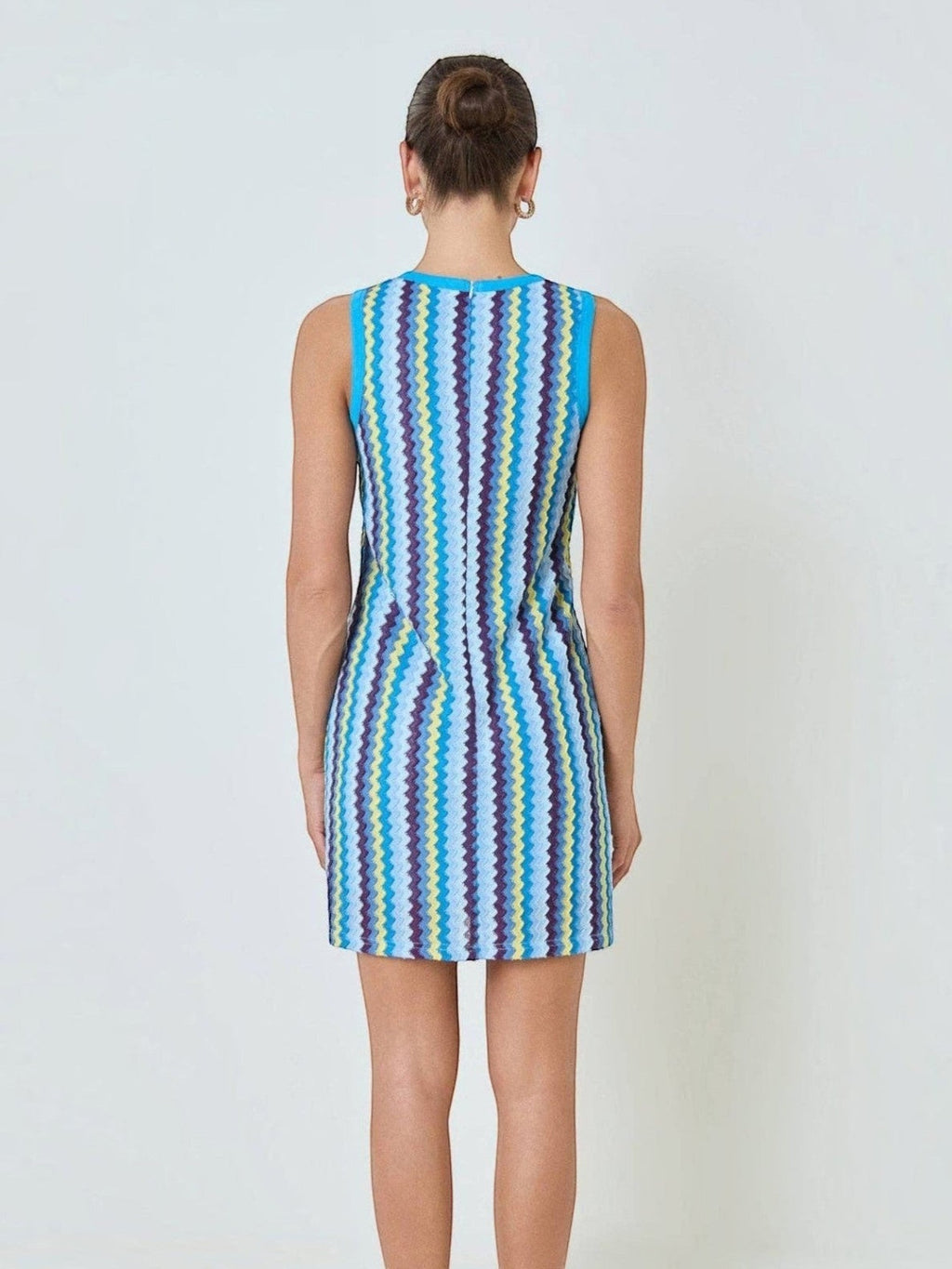 Back view of Mialur Santorini knit mini dress featuring a vibrant blue, yellow, and purple zigzag pattern.