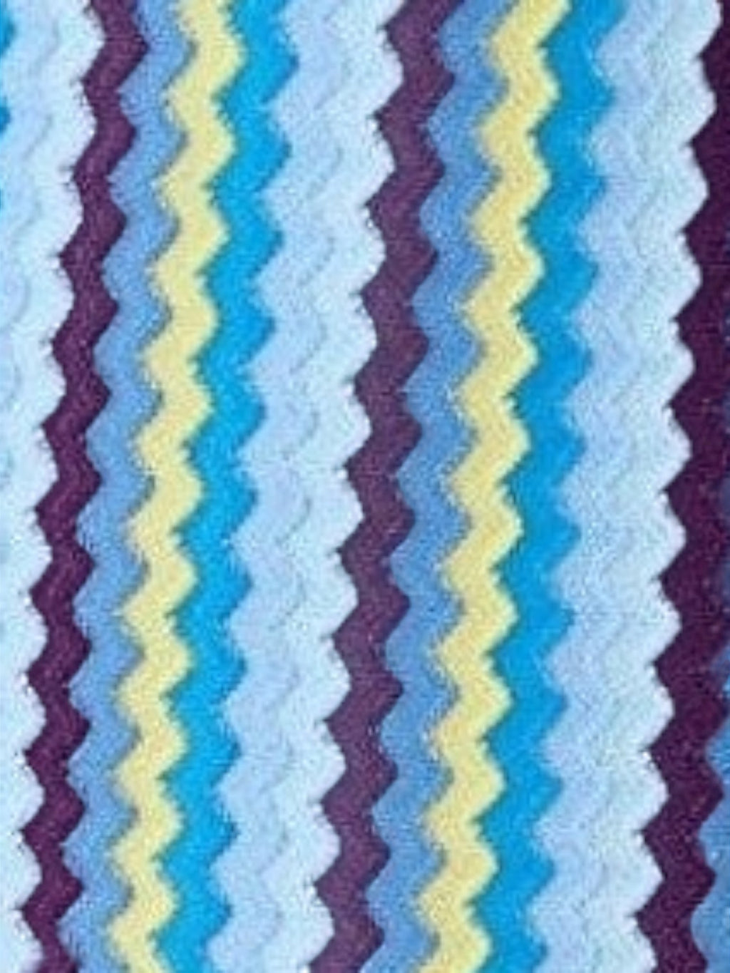 Mialur Santorini knit mini dress fabric featuring a vibrant blue, light blue, yellow, and purple zigzag pattern.