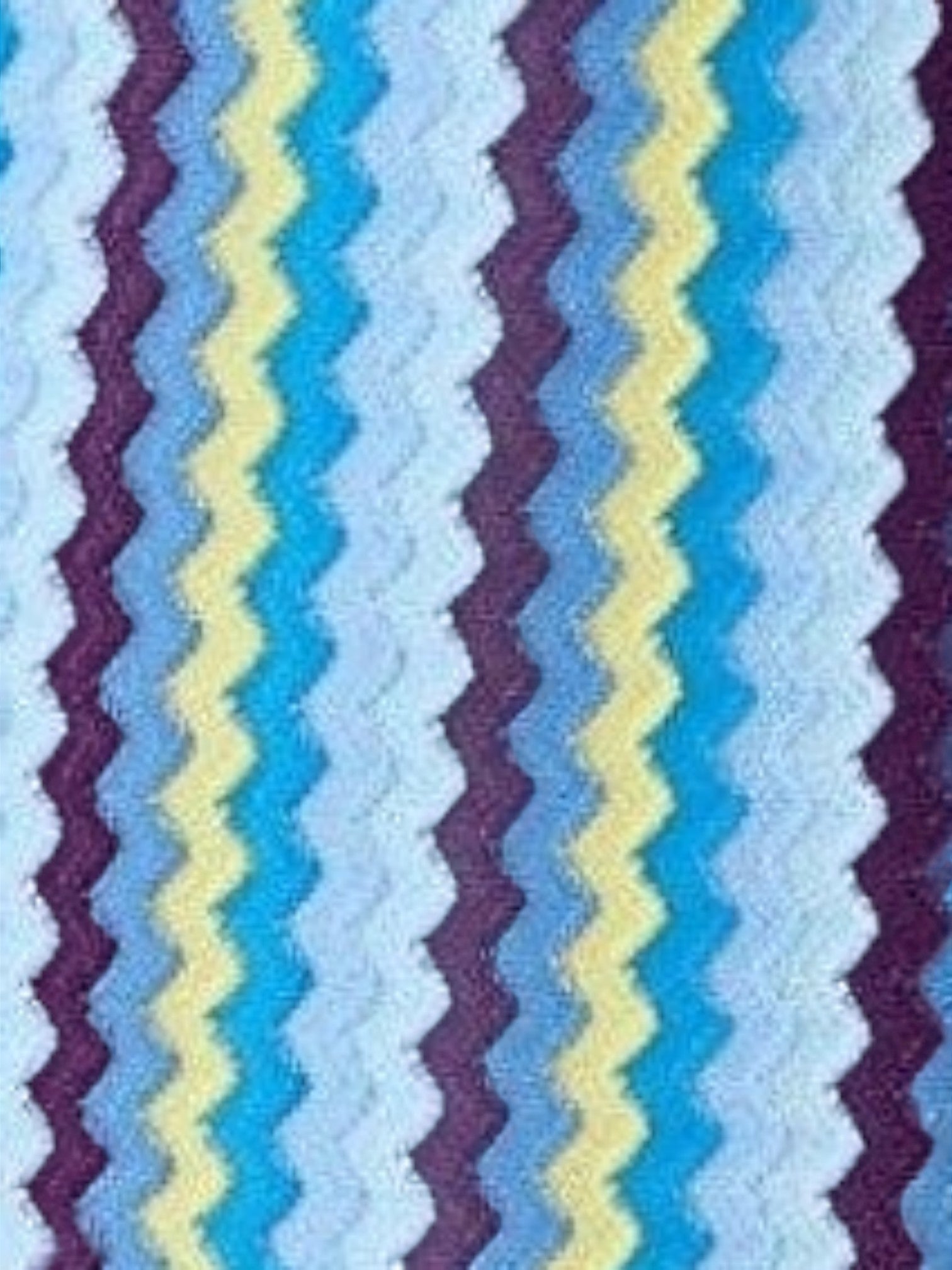 Mialur Santorini knit mini dress fabric featuring a vibrant blue, light blue, yellow, and purple zigzag pattern.