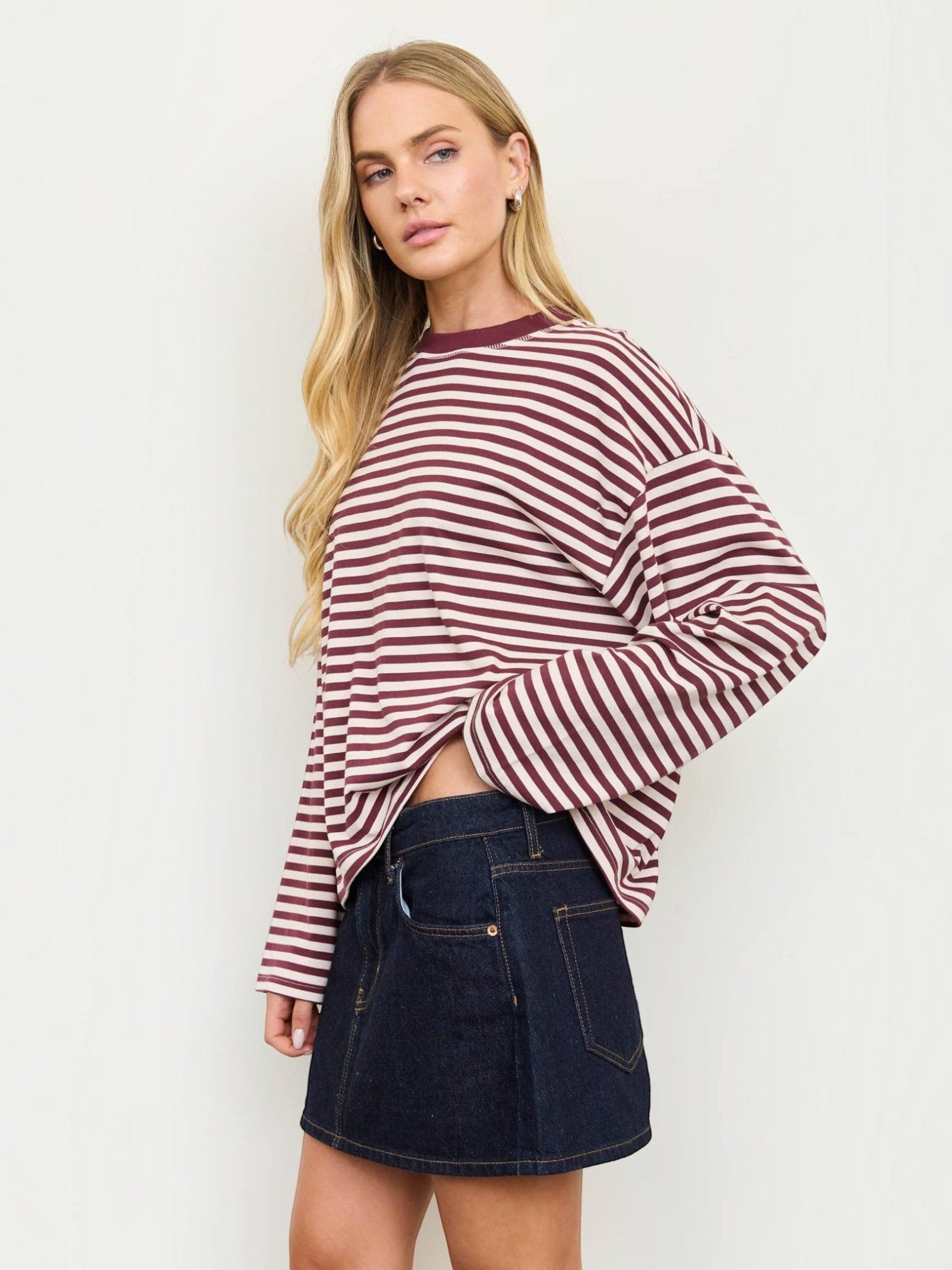 Model wearing a Mialur striped long-sleeve crew neck top with drop shoulders and contrast trim paired with a denim skirt.