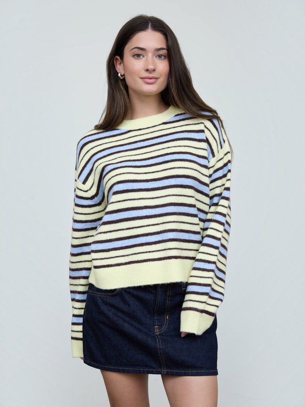 Mialur model wearing a relaxed-fit cream, light blue, and brown striped crew neck knit sweater with ribbed cuffs.