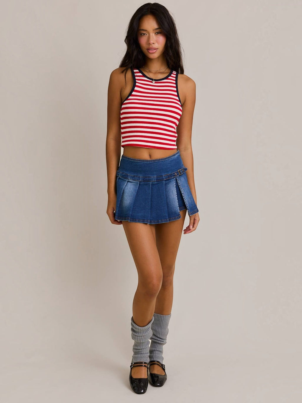Model wearing Mialur red and white horizontal striped cropped tank top with navy trim and a pleated denim mini skirt