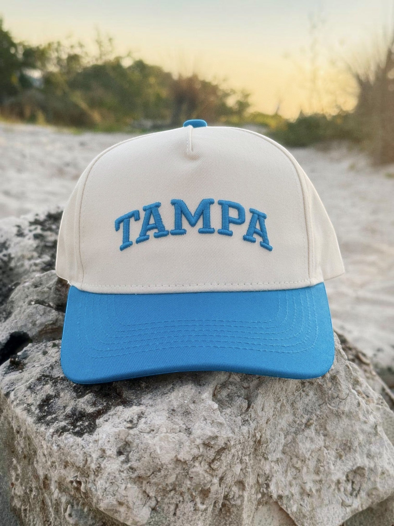 Mialur cream and blue baseball hat with TAMPA embroidered in blue lettering on a sandy beach background