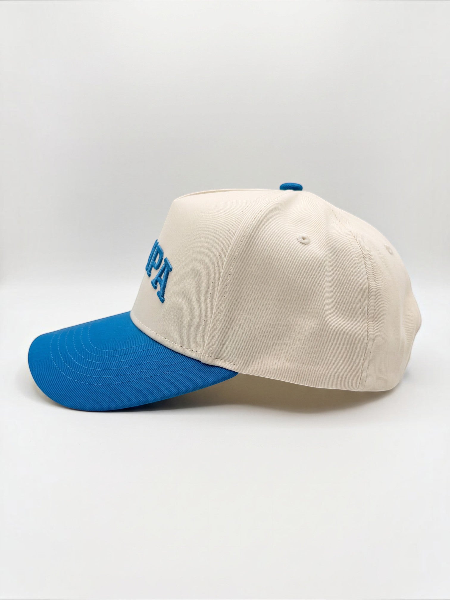 Mialur cream baseball hat with a blue curved brim and embroidered TAMPA lettering on the side profile.