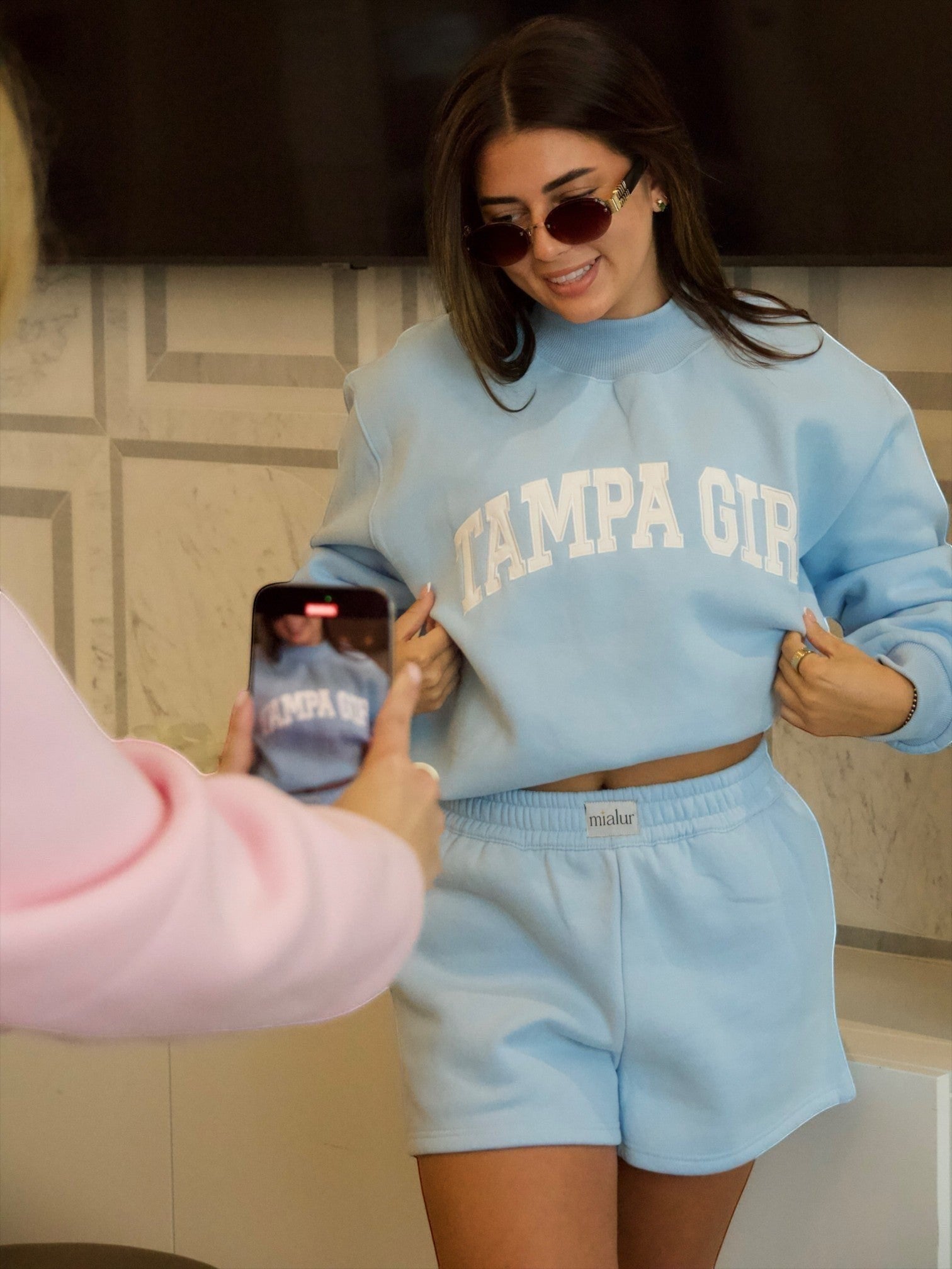 Mialur Tampa Girl light blue mock neck sweatshirt and matching shorts set worn by a woman taking a selfie