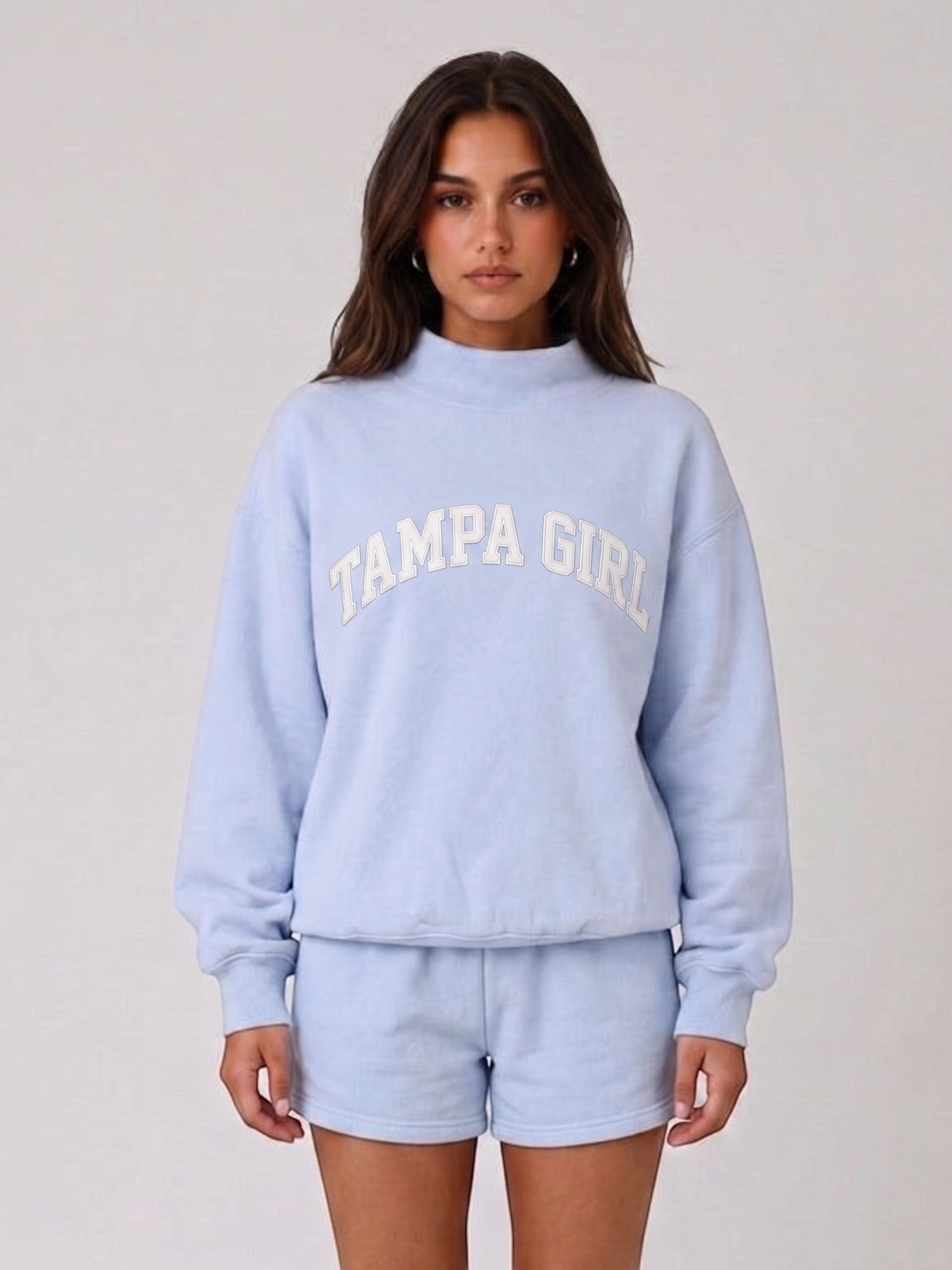 Model wearing Mialur light blue mock neck sweatshirt and matching shorts with TAMPA GIRL white graphic lettering.