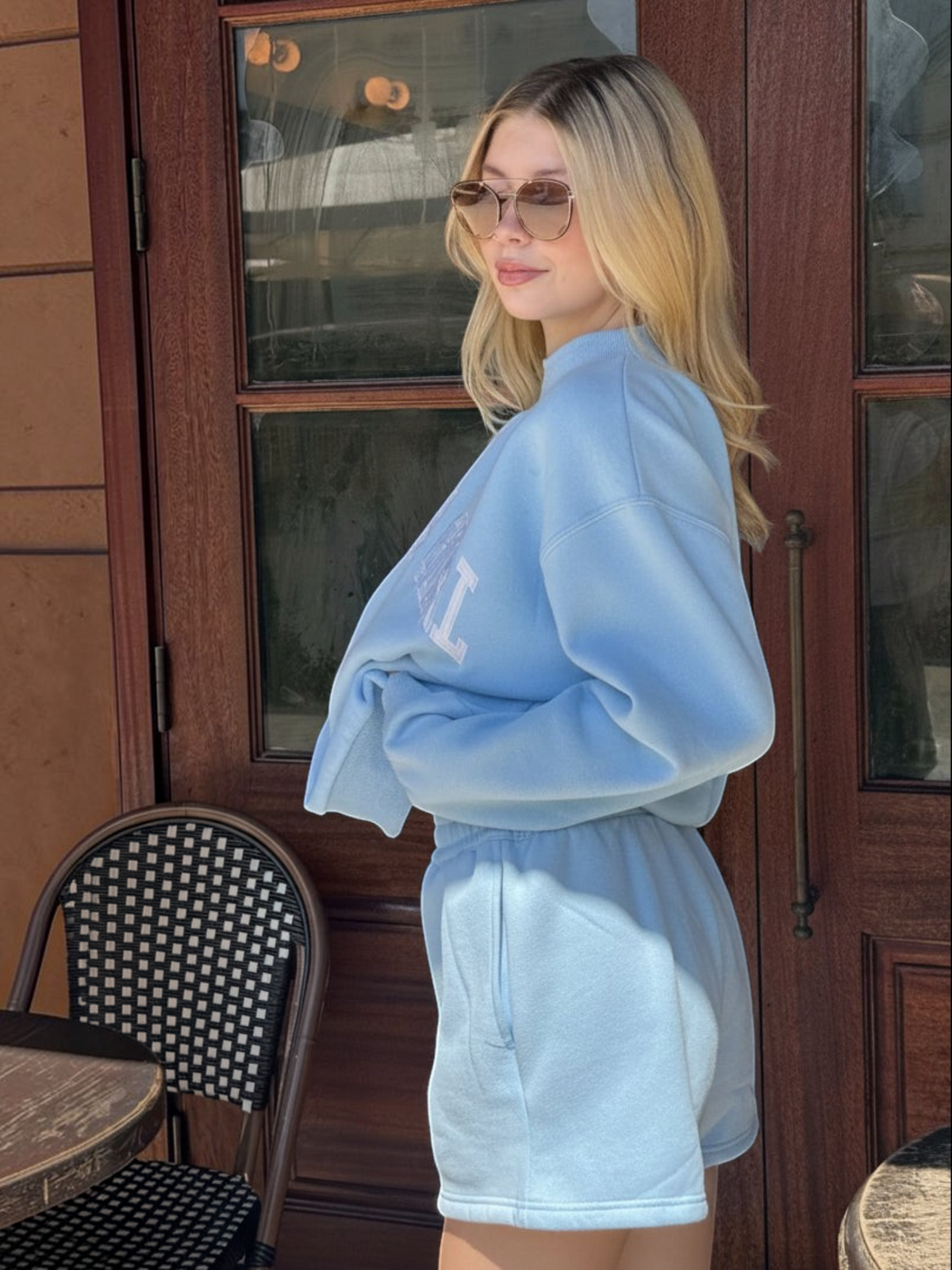 A woman wearing a Mialur light blue mock neck sweatshirt and matching shorts with white Tampa Girl lettering