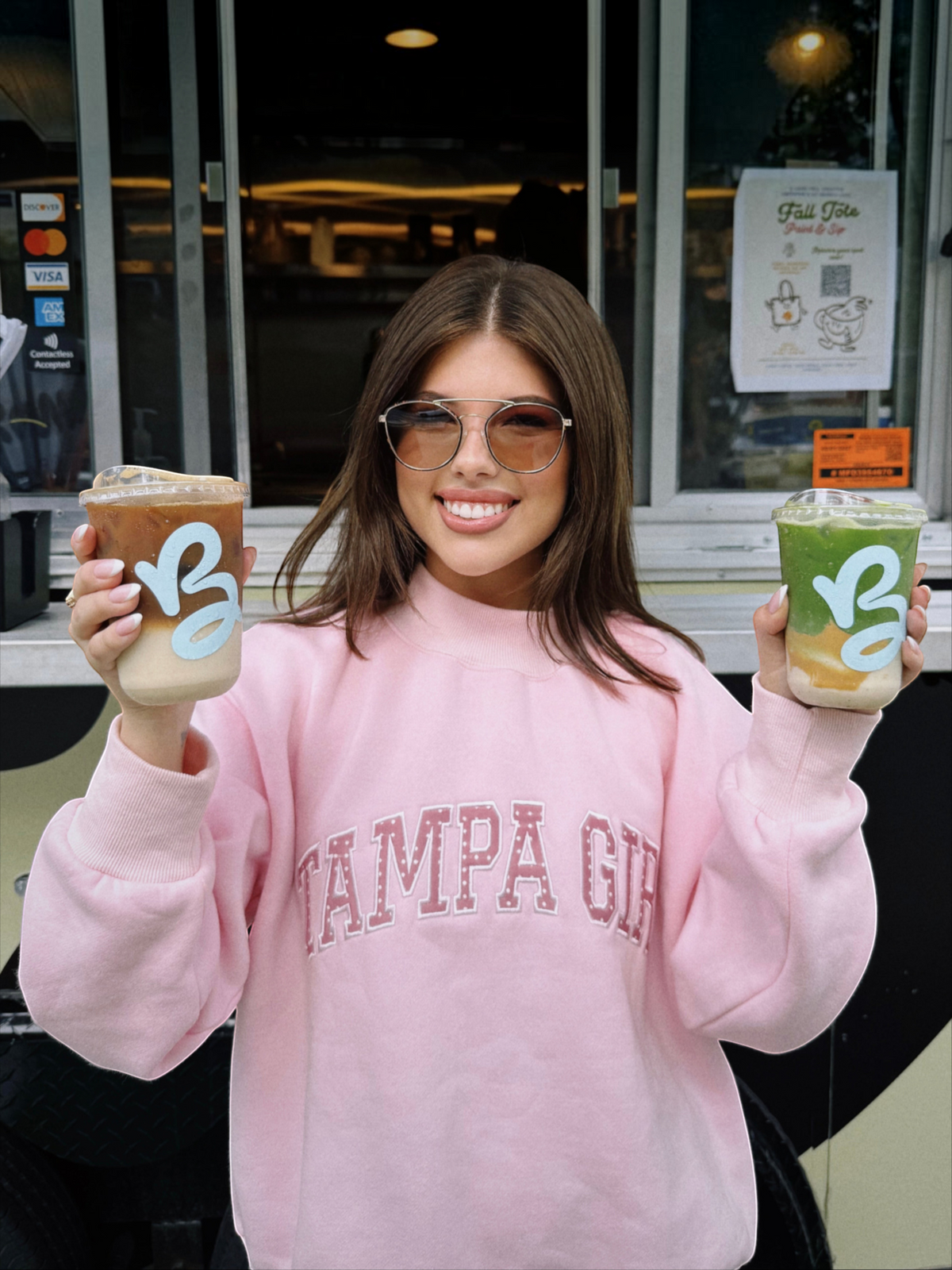 Mialur Tampa Girl light pink mock neck sweatshirt with white lettering worn by a woman holding two iced drinks