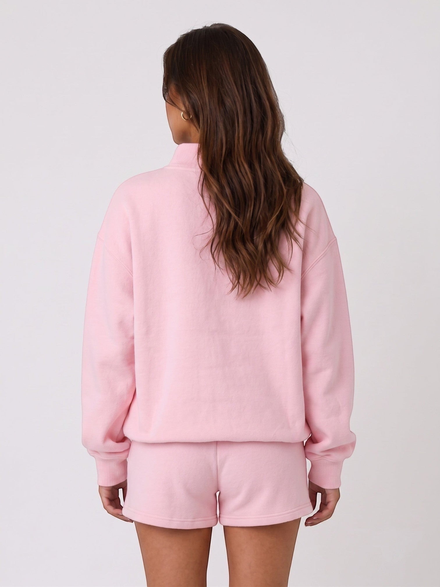 Back view of a woman wearing a Mialur light pink mock neck sweatshirt and matching shorts set.