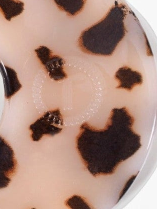 Close-up of a circular product with a tortoiseshell pattern in dark brown and beige, showing a clear plastic rim.