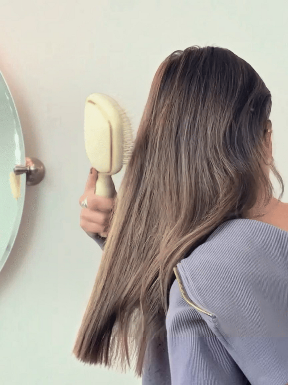 Mialur TELETIES tan detangler hair brush being used to gently brush long brown hair for smooth results.