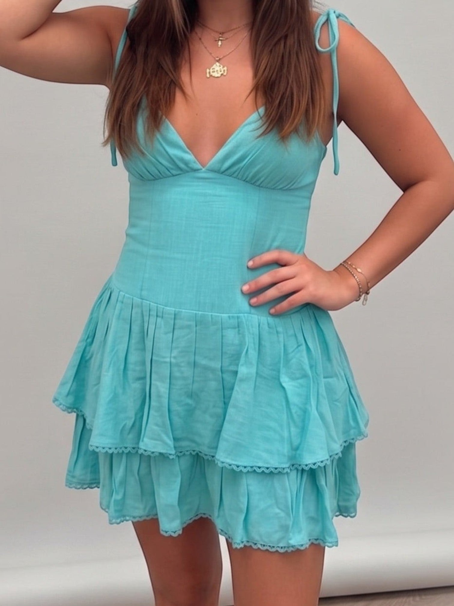 Mialur turquoise mini dress with a fitted bodice, adjustable tie straps, and a tiered skirt with scalloped trim.