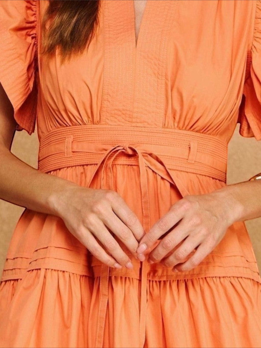 Mialur Valencia dress in cantaloupe orange featuring a smocked waist with tie detail and flutter sleeves
