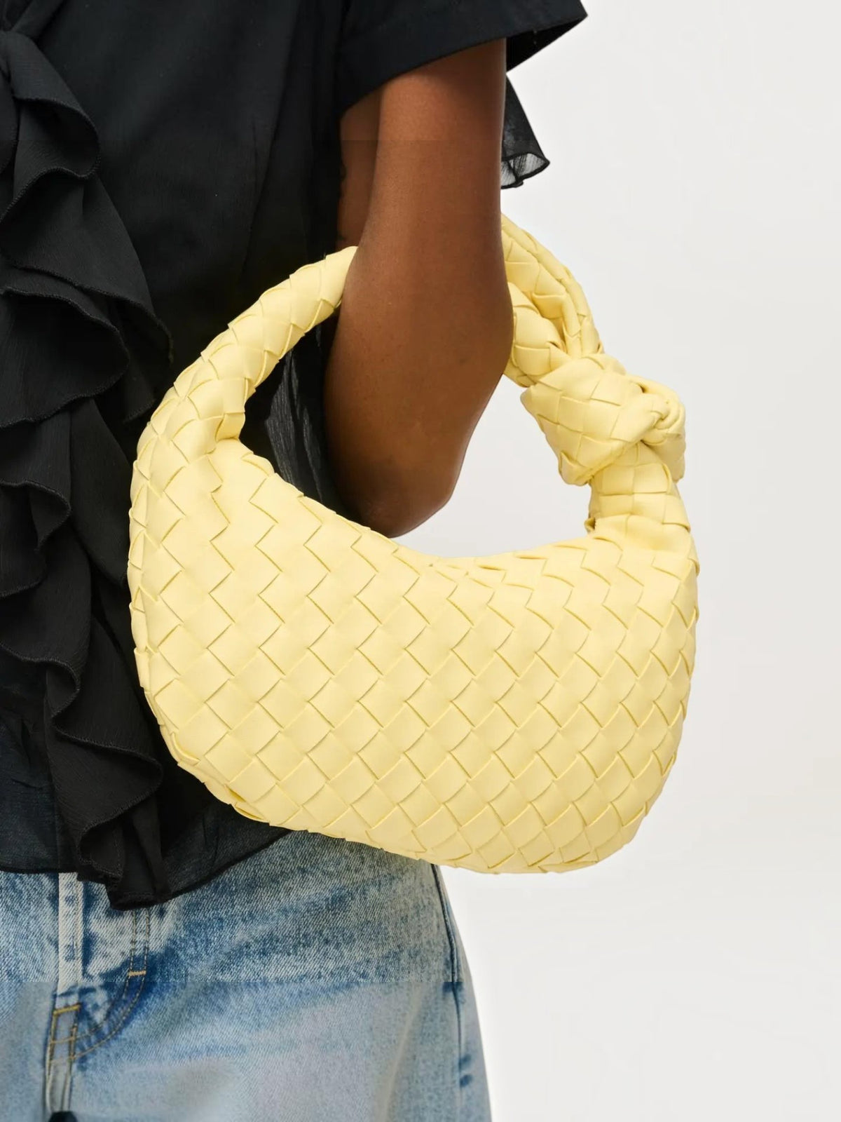 Mialur Verona Bag in butter yellow vegan leather with a woven texture and a distinctive knot handle held by a model.