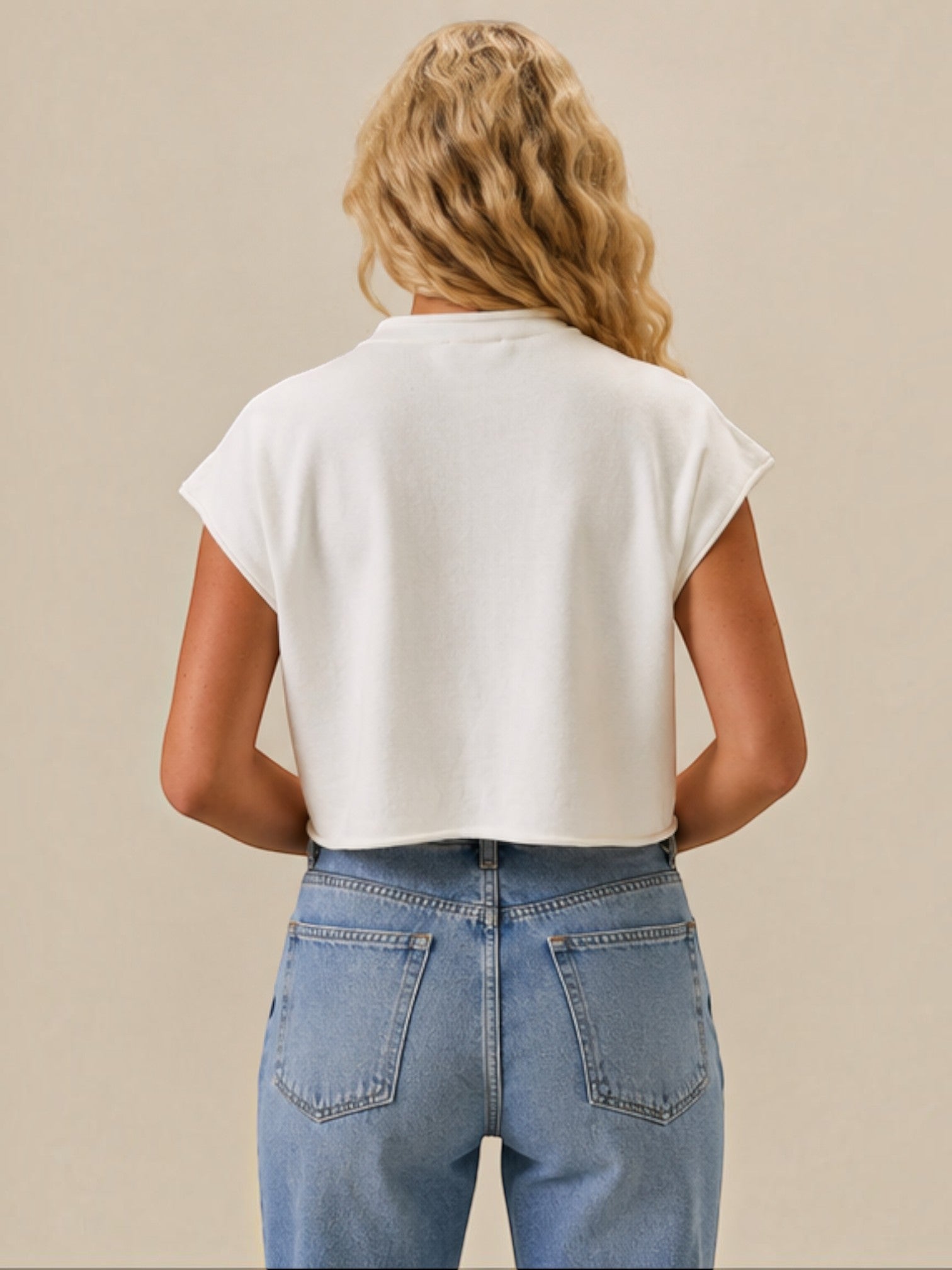 Mialur white mock neck top with a relaxed drop shoulder fit worn by a blonde woman with blue jeans, back view.