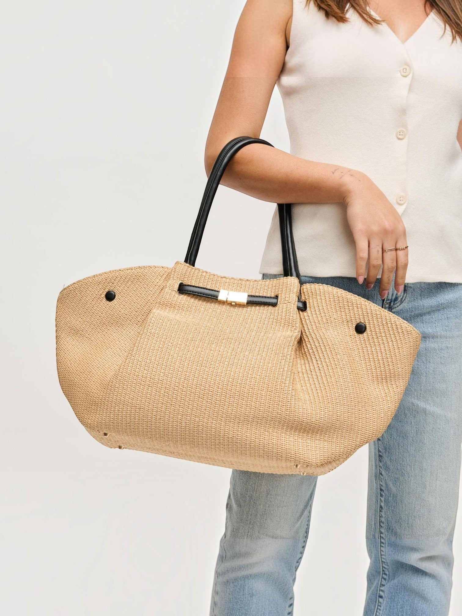 Mialur woven straw summer tote bag with black handles and a gold-tone bow clasp held by a woman in a white top.