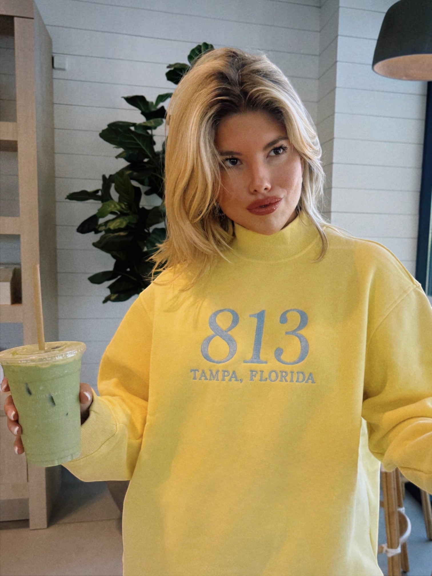 Mialur yellow cotton-blend mock neck sweatshirt with 813 Tampa Florida collegiate graphic worn by a blonde woman
