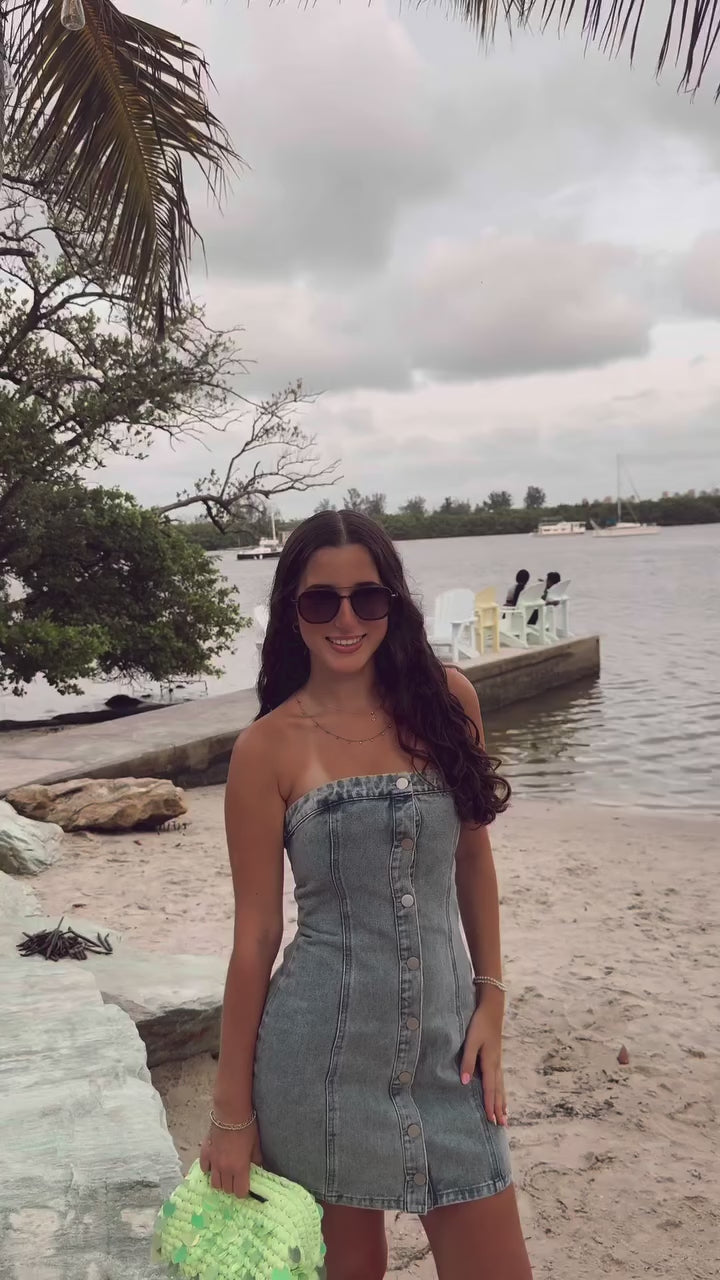 Mialur Boutique - Video of a woman wearing a denim mini dress and holding a green clutch purse on a beach